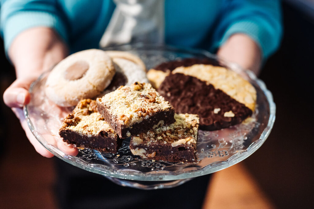Eine Person hält einen gläsernen Teller mit unterschiedlichen Gebäck.